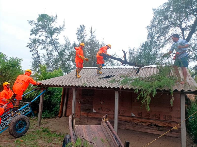 India's National Disaster Response Force (NDRF) rescuers remove fallen tree branches on the roof of a house as they oversee damages in Cyclone Remal affected villages in West Bengal state, India, Monday, May 27, 2024. (NDRF via AP)