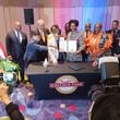 College Park Mayor Bianca Motley Broom holds up a memorandum of understanding signed with Hills Robotics CEO Muenggyu Park (center left, in tan jacket) on Saturday night, June 15, 2024. They are surrounded by business and political officials from Fulton County and Seongnam, South Korea.