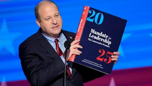 Colorado Gov. Jared Polis holds up a copy of Project 2025 as he speaks during the Democratic National Convention on Aug. 21, 2024, in Chicago. (J. Scott Applewhite/AP)