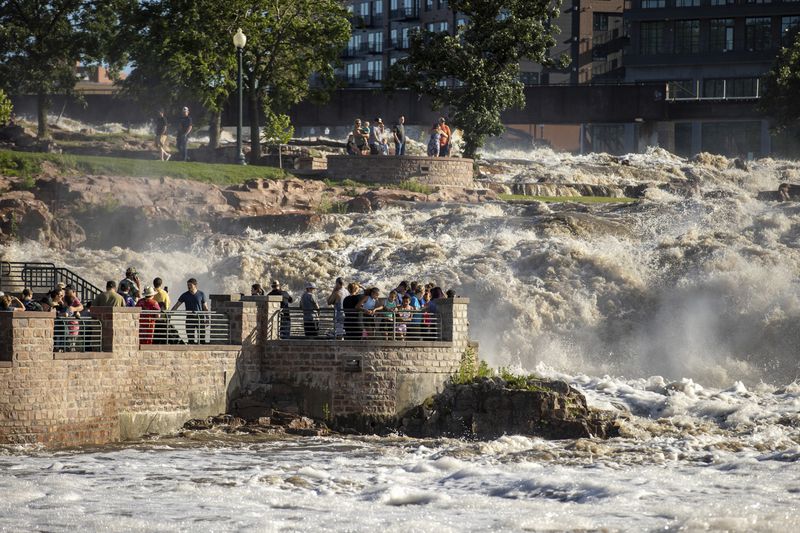 Many families embark on Falls Park in Sioux Falls, S.D., as water rose quickly Saturday, June 22, 2024, after days of heavy rain led to flooding in the area. (AP Photo/Josh Jurgens)