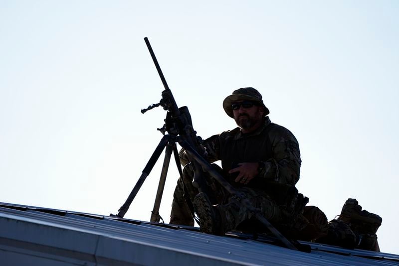 A counter sniper sets up on the roof of a building before Republican presidential nominee former President Donald Trump speaks at a campaign rally at the Butler Farm Show, the site where a gunman tried to assassinate him in July, Saturday, Oct. 5, 2024, in Butler, Pa. (AP Photo/Alex Brandon)