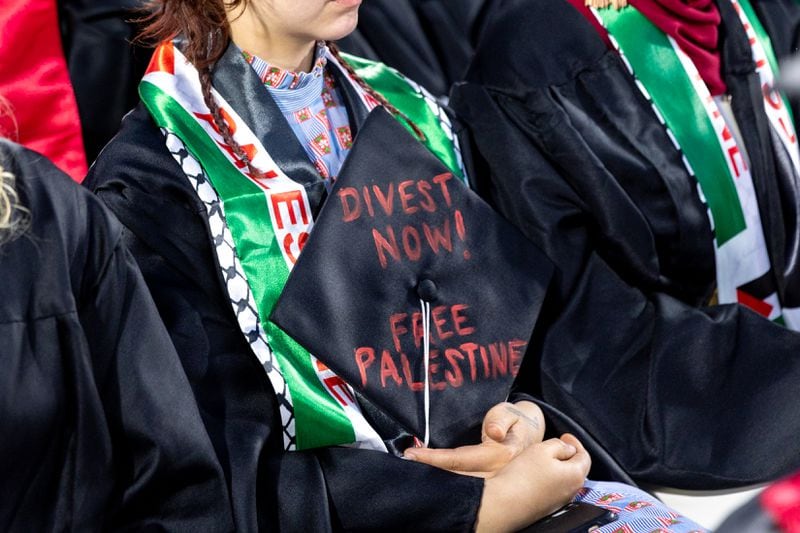 A graduate holds a graduation cap with a pro-Palestinian message in Sanford Stadium during the University of Georgia spring commencement in Athens on Friday, May 10, 2024. (Arvin Temkar / AJC)