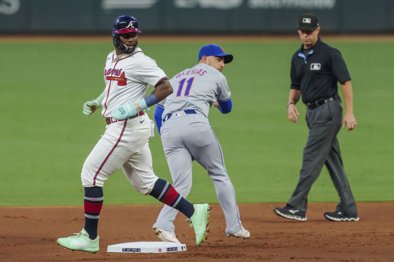 New York Mets second baseman Jose Iglesias, center, tags Atlanta Braves' Michael Harris II, left, out at second base and then attempts to throw out Ozzie Albies (1) at first base in the first inning of a baseball game, Tuesday, Sept. 24, 2024, in Atlanta. (AP Photo/Jason Allen)