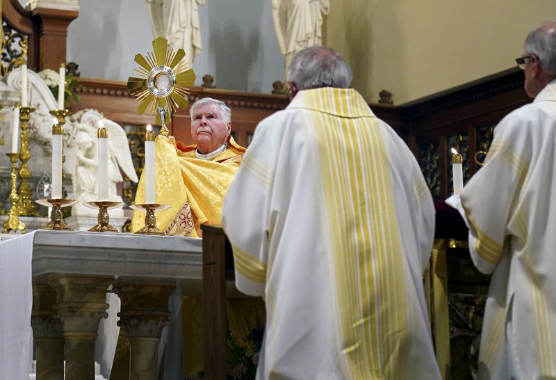 Bishop Paul Bradley raises the Eucharist during a prayers service at St. Peter Church in Steubenville, Ohio, Friday, June 21, 2024. The service was part of the National Eucharistic Pilgrimage, which seeks to raise devotion around a sacrament in which Catholics believe they encounter Jesus' real presence. (AP Photo/Jessie Wardarski)