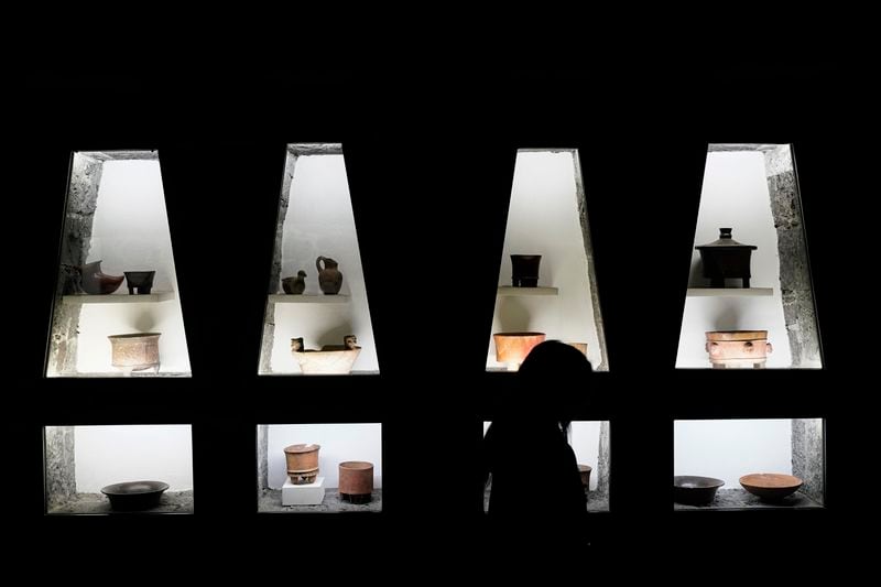 A visitor walks past pre-Hispanic ceramics displayed in glass front niches in the Anahuacalli Museum in Mexico City, Tuesday, Aug. 20, 2024. Built by Mexican artist Diego Rivera to preserve and display his lifelong collection of pre-Hispanic art, the museum is celebrating its 60th anniversary. (AP Photo/Eduardo Verdugo)