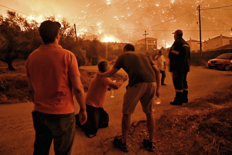 A resident reacts as a wildfire approaches the village of Ano Loutro as fanned by strong winds raged uncontrolled despite the attempts of hundreds of firefighters to stop it, some 131 kilometers (81 miles) west of Athens, Greece, in the region of Corinthia, late Sunday, Sept. 29, 2024. (AP Photo)