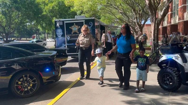 4-year-old Armon (left) and his brother Ashton tour the array of cars brought by the Muscogee County Sheriff’s Office. Sheriff Greg Countryman organized the special day after learning Armon dreamed of becoming an officer. (Photo Courtesy of Bea Lunardini)