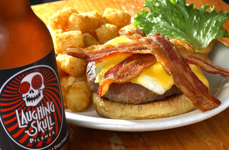 The Vortex Classic Coronary burger with tater tots and a Laughing Skull beer. AJC FILE PHOTO