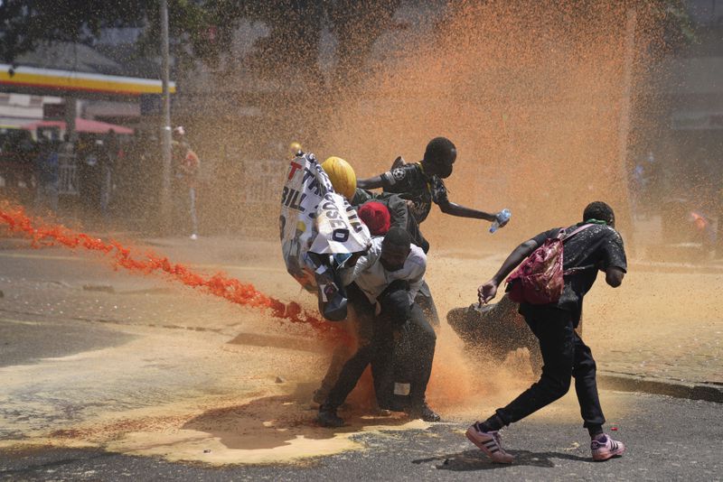 Protesters scatter as Kenya police spray water canon at them during a protest over proposed tax hikes in a finance bill in downtown Nairobi, Kenya Tuesday, June. 25, 2024. (AP Photo/Brian Inganga)