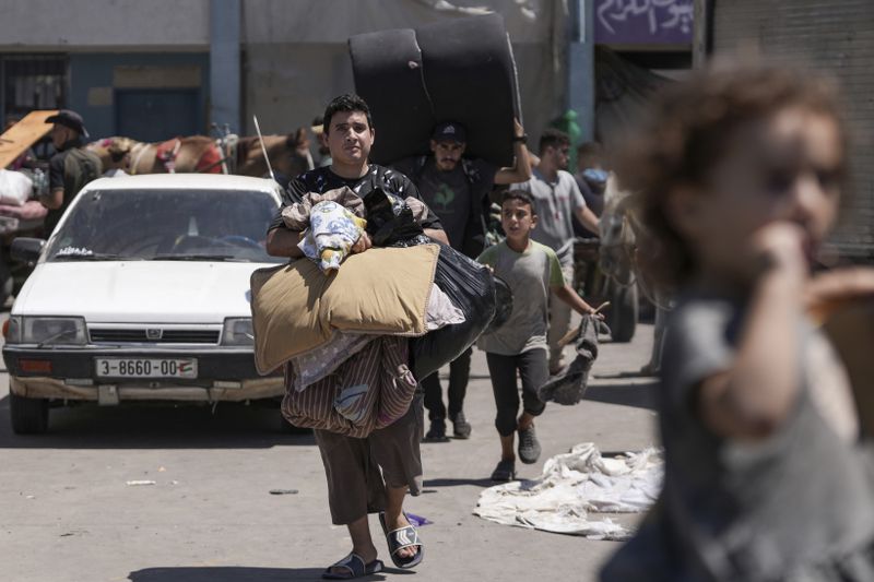 Palestinians evacuate a school that had been their shelter, in eastern Deir al-Balah, Gaza Strip, Friday, Aug. 16, 2024, after the Israeli military dropped leaflets asking civilians to evacuate from the area and northern Khan Younis, saying forces plan to respond to rocket fire that targeted Israel. (AP Photo/Abdel Kareem Hana)