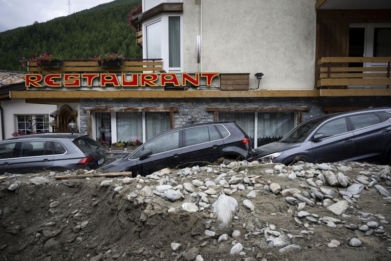 Cars stuck in the rubble from a landslide caused by severe weather following storms that caused major flooding and landslide are pictured in Saas-Grund, Switzerland, Sunday, June 30, 2024. Authorities say weekend storms in Switzerland and northern Italy caused extensive flooding and landslides, leaving at least four people dead. Storms and heavy rain affected southern and western Switzerland on Saturday and overnight. (Olivier Maire/Keystone via AP)
