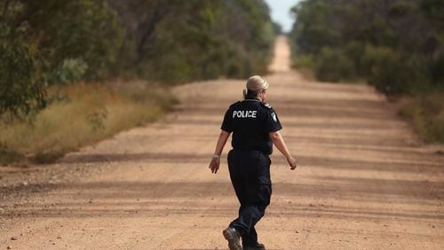A Police officers walks across a road near the scene of a fatal shooting in Wieambilla, Australia, Dec. 13, 2022. Three Christian extremists who killed two police officers, a bystander and wounded a third police officer in an ambush on a rural Australian property in 2022 had been bent on intimidating state authorities, a coroner was told on Monday, July 29, 2024. (Jason O'Brien/AAP Image via AP)