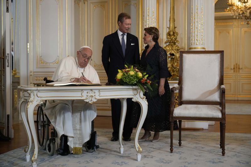 Pope Francis flanked by Luxembourg's Grand Duke Henri and Grand Duchess Maria Teresa signs the guest book during his visit at the Grand Ducal Palace, in Luxembourg, Thursday, Sept. 26, 2024. (AP Photo/Andrew Medichini)