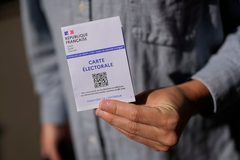 A man shows his voting card in a voting station during the European election, Sunday, June 9, 2024 in Paris. Polling stations opened across Europe on Sunday as voters from 20 countries cast ballots in elections that are expected to shift the European Union's parliament to the right and could reshape the future direction of the world's biggest trading bloc. (AP Photo/Lewis Joly)