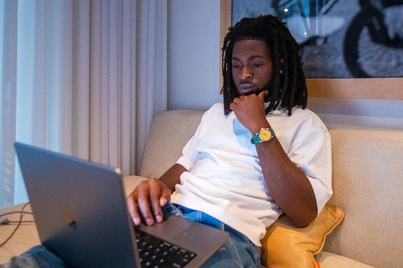 Looking comfortable while concentrating, Justice Baiden, Love Renaissance's head of A&R, works in his Castleberry Hill office. (Ziyu Julian Zhu/AJC)