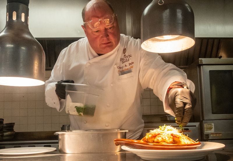 Chef Gary Palm sprinkles parsley on a hot brown just before it is served at the Brown Hotel in Louisville, Kentucky. (Bill Dawers for The Atlanta Journal-Constitution)