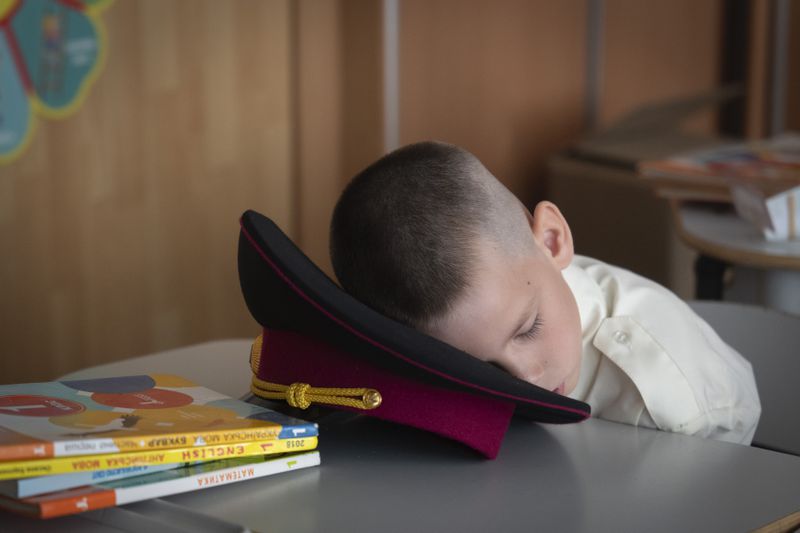 A young cadet takes a nap at the first lesson in a cadet lyceum on the first day at school in Kyiv, Ukraine, Monday, Sept. 2, 2024. Children and students went to school despite the fact that Kyiv was hit by massive Russian missile barrage early in the morning, causing fires, damaged buildings and infrastructure objects. (AP Photo/Efrem Lukatsky)