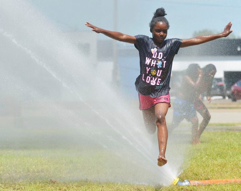 Serena Porter, 9, stays cool as she runs through water provided by the Benton Harbor Department of Public Safety during Spray and Play on Tuesday, June 18, 2024, at City Center Park in downtown Benton Harbor, Mich. (Don Campbell/The Herald-Palladium via AP)