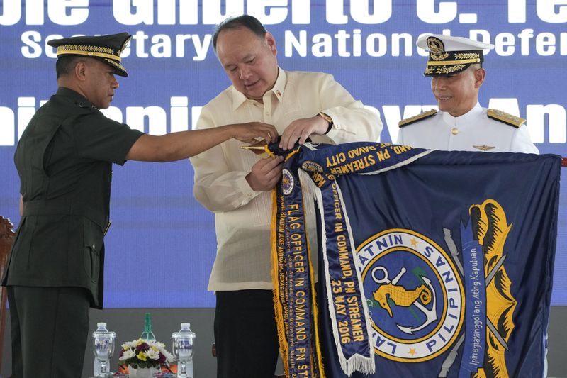 Philippine Defense Secretary Gilberto Teodoro, center, and military chief Romeo Brawner Jr., left, place an award on a flag during the 126th Philippine Navy anniversary in Manila, Philippines on Friday, May 24, 2024. The Philippines would press efforts to build security alliances and stage realistic combat drills, including joint naval sails with the United States, Japan and Australia in disputed waters, to defend its territorial interests, Defense Secretary Gilberto Teodoro said Friday, dismissing China's criticisms of such moves as a sign of paranoia. (AP Photo/Aaron Favila)