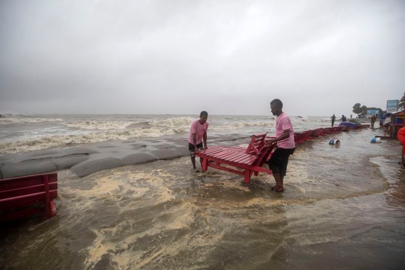 Men salvage a reclining chair and other material as water flows on to the Kuakata beach on the coast of Bay of Bengal caused by the advancing Cyclone Remal in Barisal, Bangladesh, Sunday, May 26, 2024. (AP Photo/Abdul Goni)