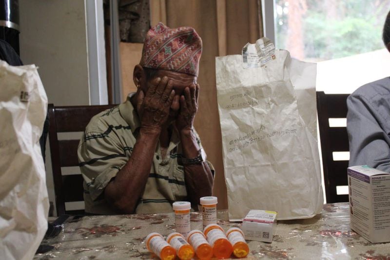 Jit Bahadur covers his eyes after pulling out bags of medicine. (Photo Courtesy of Sophia Qureshi)