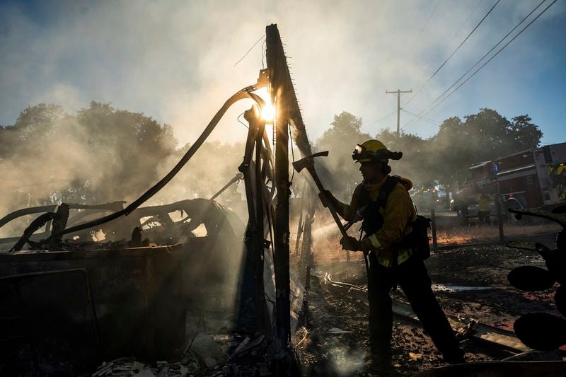 Firefighter Jonathan Lievanos extinguishes hot spots at a home destroyed by the Boyles fire in Clearlake, Calif., on Sunday, Sept. 8, 2024. (AP Photo/Noah Berger)