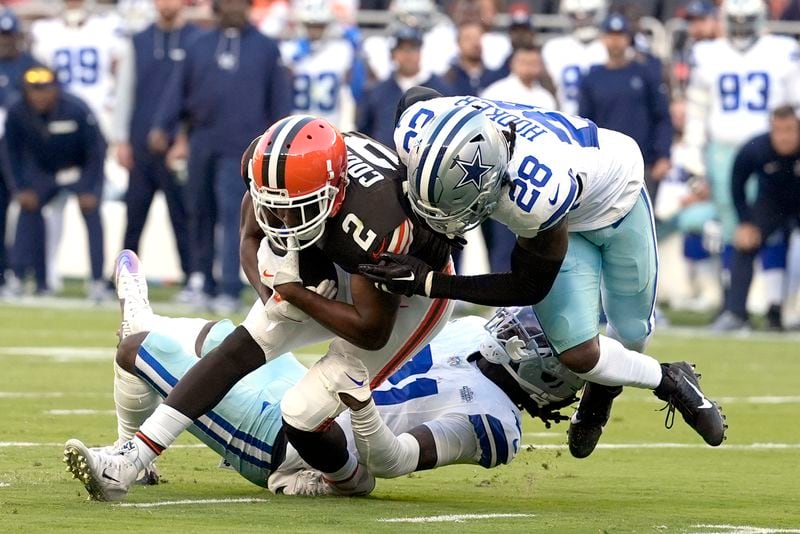 Cleveland Browns wide receiver Amari Cooper (2) is stopped after making a catch by Dallas Cowboys safety Malik Hooker (28) and cornerback Caelen Carson, rear, in the second half of an NFL football game in Cleveland, Sunday, Sept. 8, 2024. (AP Photo/Sue Ogrocki)