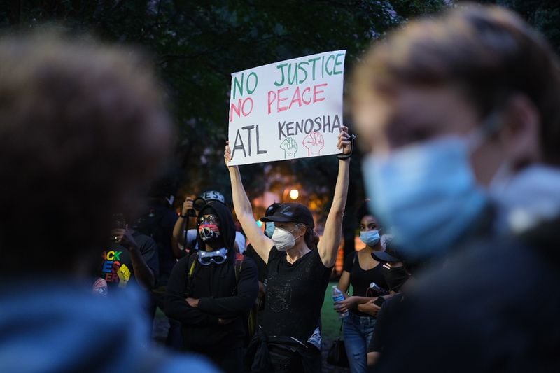 Jan Rivers holds up a sign during a protest at Woodruff Park in downtown Atlanta Tuesday evening.