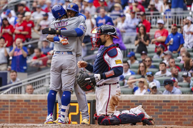 New York Mets' Francisco Lindor, left, and Starling Marte, center, celebrate at home plate after scoring in the ninth inning of a baseball game against the Atlanta Braves, Monday, Sept. 30, 2024, in Atlanta. (AP Photo/Jason Allen)