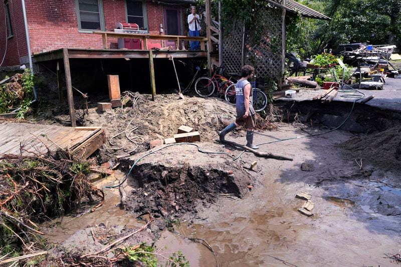 August Thompson walks over the washed out remains of the road in front of his grandfather's home after remnants of Hurricane Beryl caused flooding and destruction, Friday, July 12, 2024, in Plainfield, Vt. (AP Photo/Charles Krupa)