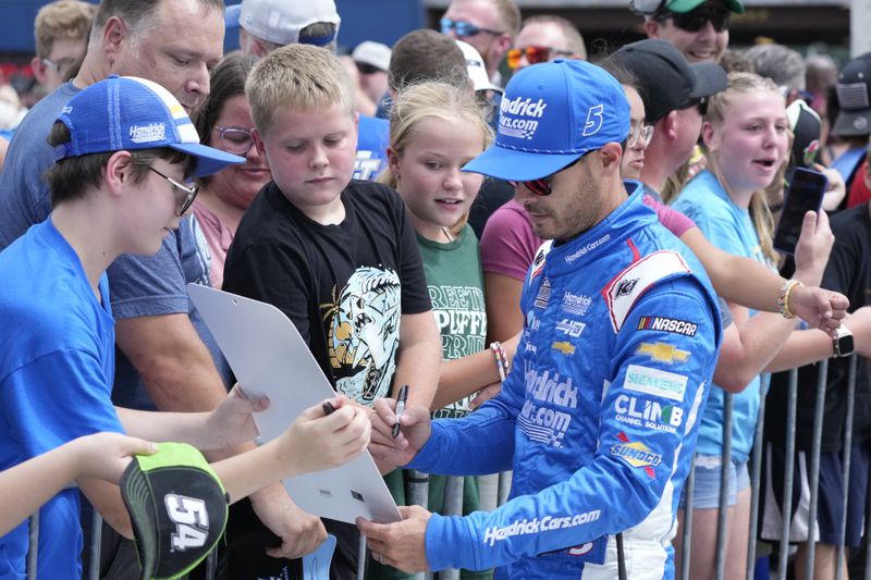 Kyle Larson signs autographs before driver introductions of a NASCAR Cup Series auto race at Michigan International Speedway, Sunday, Aug. 18, 2024, in Brooklyn, Mich. (AP Photo/Carlos Osorio)