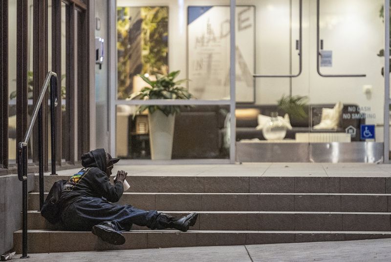 A man lays on the front steps of an office building early morning Wednesday, June 26, 2024 in the West Lake area of Los Angeles. The number of homeless residents counted in Los Angeles County has dipped slightly, decreasing by about 0.3% since last year as California continues to struggle with the long-running crisis of tens of thousands of people sleeping in cars and encampments. (AP Photo/Damian Dovarganes)