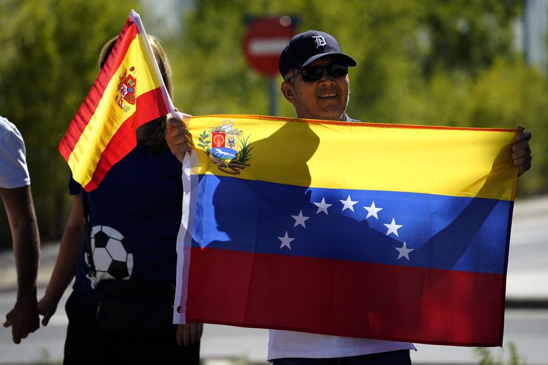 Supporters of Edmundo González gather outside the Torrejón Air Base in Madrid, Spain, Sunday, Sept. 8, 2024. Former Venezuelan opposition presidential candidate Edmundo González has fled into exile after being granted asylum in Spain, delivering a major blow to millions who placed their hopes in his upstart campaign to end two decades of single-party rule. (AP Photo/Andrea Comas)