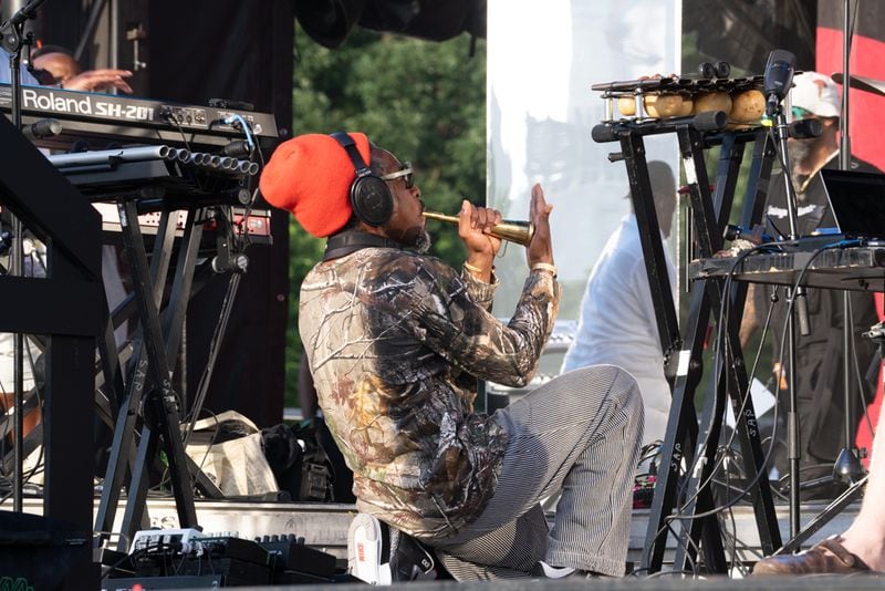 Andre 3000 kneels onstage while playing flute at the 2024 Atlanta Jazz Festival on May 27, 2024.