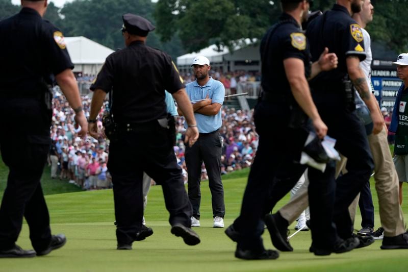 Protesters are led away after they ran onto the course as Scottie Scheffler, center, looks on at the 18th hole during the final round of the Travelers Championship golf tournament at TPC River Highlands, Sunday, June 23, 2024, in Cromwell, Conn. (AP Photo/Seth Wenig)