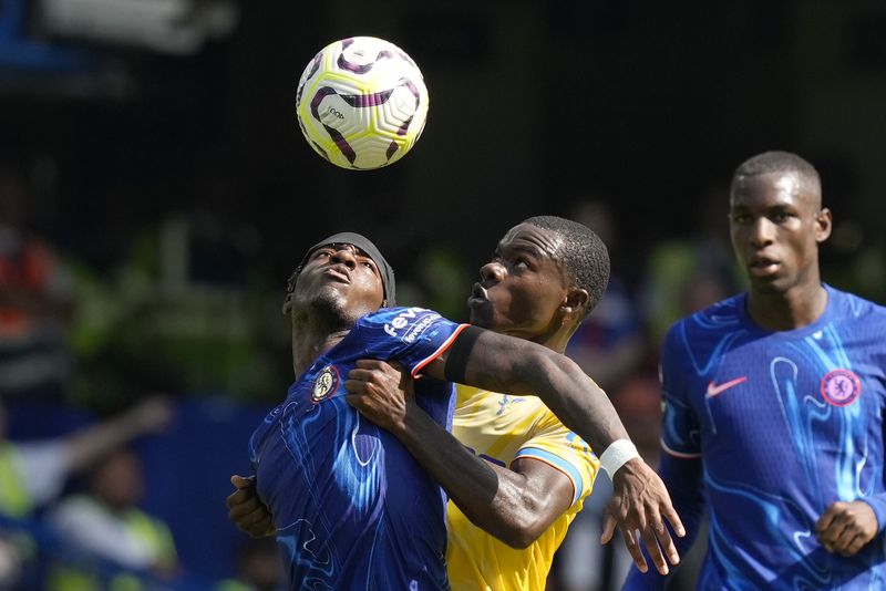 Chelsea's Noni Madueke, left, and Crystal Palace's Tyrick Mitchell, center, fight for the ball during the English Premier League soccer match between Chelsea and Crystal Palace, at the Stamford Bridge Stadium in London, Sunday, Sept. 1, 2024. (AP Photo/Frank Augstein)