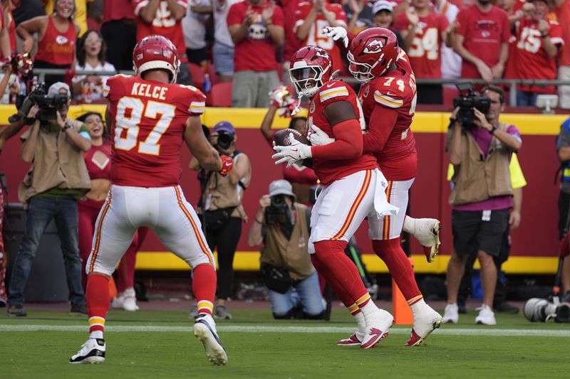 Kansas City Chiefs offensive lineman Wanya Morris, center, is congratulated by teammates Travis Kelce (87) and Jawaan Taylor (74) after catching a touchdown pass during the second half of an NFL football game against the Cincinnati Bengals Sunday, Sept. 15, 2024, in Kansas City, Mo. (AP Photo/Ed Zurga)