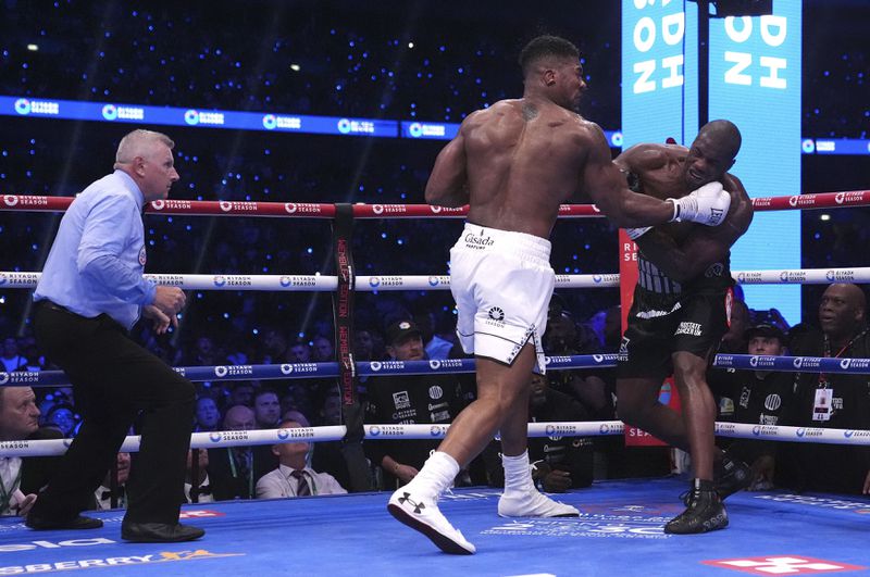 Anthony Joshua, centre, and Daniel Dubois, right, fight in the IBF World Heavyweight bout at Wembley Stadium, in London, Saturday, Sept. 21, 2024. (Bradley Collyer/PA via AP)