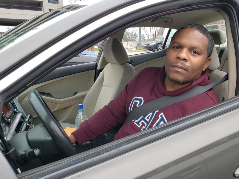 Lyft and Uber driver Omar Holland, picking up a rider in Doraville, worries about the chances of being exposed to COVID-19 on the job and then spreading it to his family at home in Marietta. MATT KEMPNER / AJC