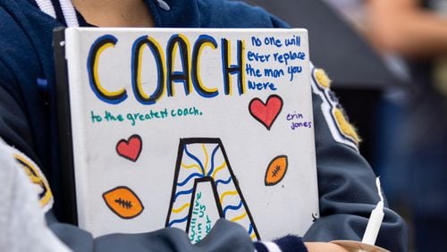 A mourner holds a sign honoring Apalachee High School football assistant coach Richard “Ricky” Aspinwall at a vigil at Jug Tavern Park in Winder on Friday, Sept. 6, 2024. A 14-year-old Apalachee High School student is accused of shooting and killing two fellow students, Aspinwall and another teacher and injuring nine others at the Barrow County high school on Wednesday.