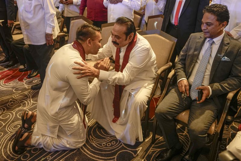 FILE - Presidential candidate Namal Rajapaksa bows down before his father and former president Mahinda Rajapaksa during the launching of his election manifesto in Colombo, Sri Lanka, Monday, Sept. 2, 2024. (AP Photo/Eranga Jayawardena, File)