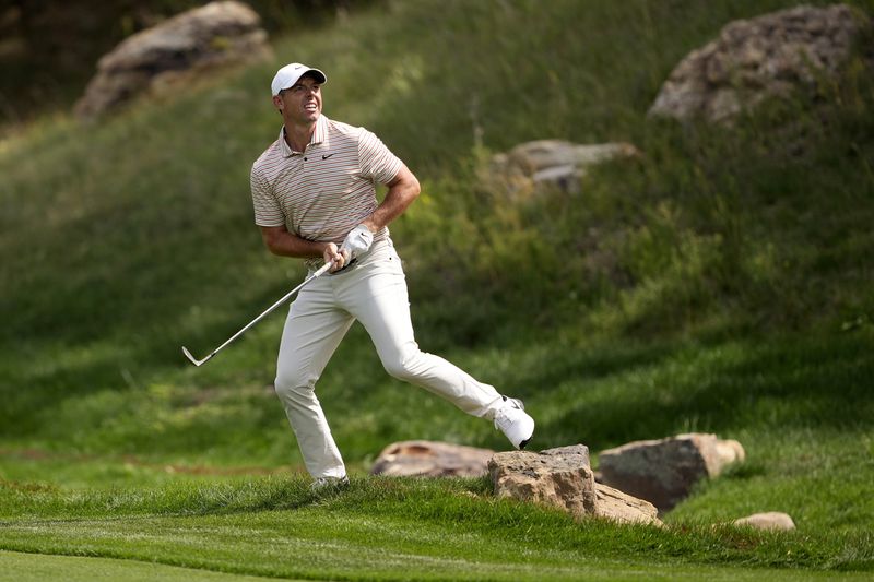 Rory McIlroy, of Northern Ireland, jumps off a rock after playing his shot in the 17th fairway during the first round of the BMW Championship golf event at Castle Pines Golf Club, Thursday, Aug. 22, 2024, in Castle Rock, Colo. (AP Photo/Matt York)