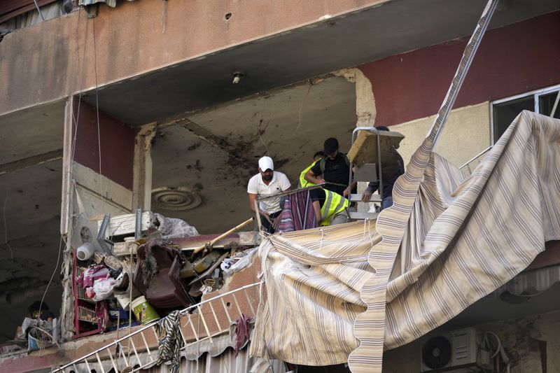 Residents and rescuers check a building that was hit by an Israeli airstrike in Beirut's southern suburbs, Tuesday, Sept. 24, 2024. (AP Photo/Hassan Ammar)