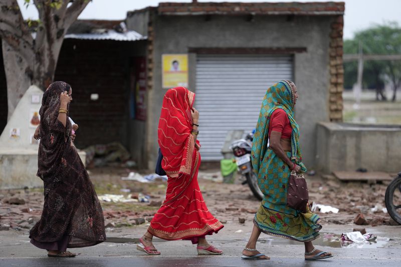 Villagers walk towards the site of Tuesday's stampede in Hathras district, Uttar Pradesh, India, Wednesday, July 3, 2024. Thousands of people at a religious gathering rushed to leave a makeshift tent, setting off a stampede Tuesday that killed more than hundred people and injured scores. (AP Photo/Rajesh Kumar Singh)