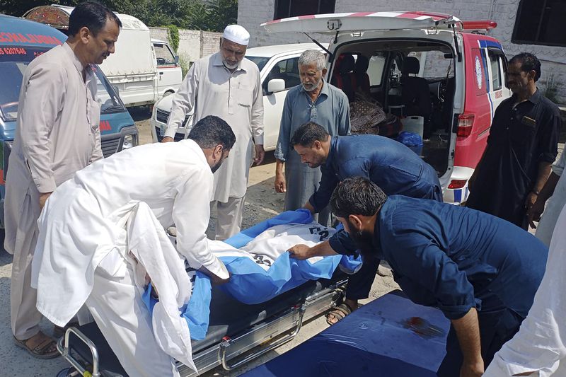 Volunteers and relatives prepare to load the body of a woman, who was killed when a passenger bus fell into a ravine, into an ambulance at a hospital in Kahuta, Pakistan, Sunday, Aug. 25, 2024. (AP Photo/Mohammad Yousaf)