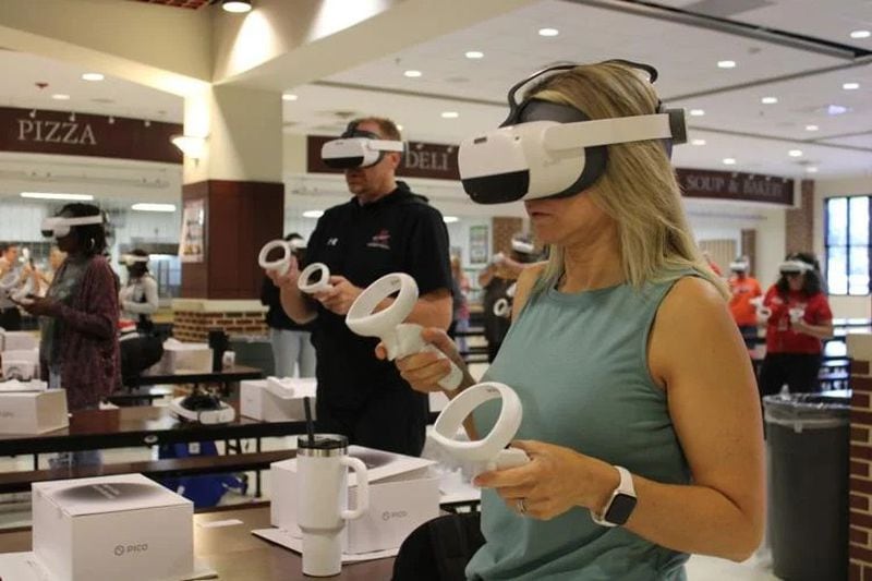 Roughly 400 of Cobb’s math and science teachers were trained to use Prisms VR headsets at Wheeler High School. Here, two teachers practice using their headset and controllers. (Photo Courtesy of Annie Mayne)