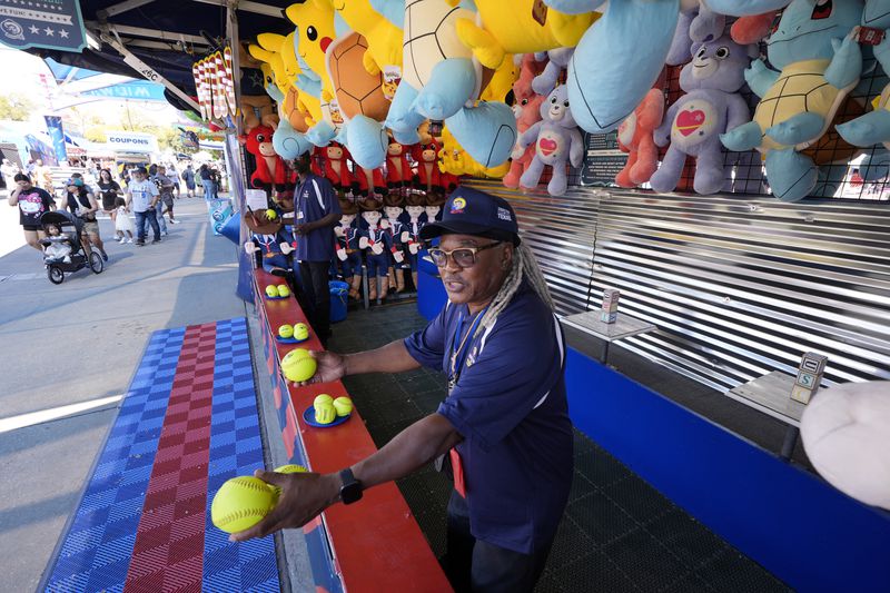 Artis Frank calls out to guests as they walk past a game attraction on the Super Midway at the State Fair of Texas in Dallas, Friday, Sept. 27, 2024. (AP Photo/Tony Gutierrez)