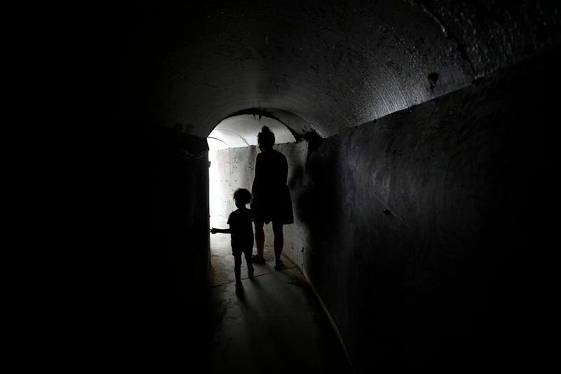 A woman and child walk through a replica of a tunnel used by Hamas militants in the Gaza Strip, ahead of a weekly protest by families of hostages held by the group to demand their release, in Tel Aviv, Israel, Saturday, Aug. 17, 2024. (AP Photo/Tsafrir Abayov)