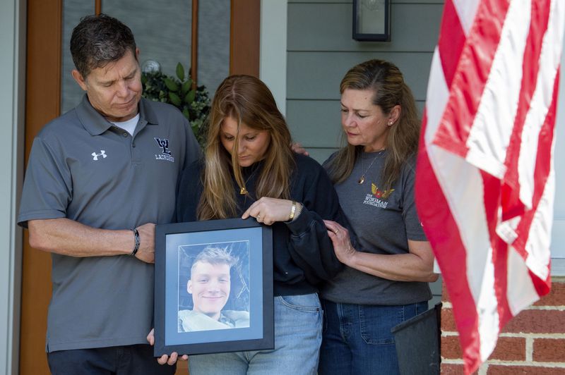 Family members of Marine Corporal Spencer R. Collart, from left, father Bart Collart, sister Gwyneth Collart and mother Alexia Collart, hold his portrait as they pose for a photo at their home in Arlington, Va., Thursday, June 19, 2024. Collart, 21, was killed along with two other Marines when the MV-22B Osprey aircraft they were on crashed during drills on a north Australian island on August 27, 2023. (AP Photo/Rod Lamkey, Jr.)