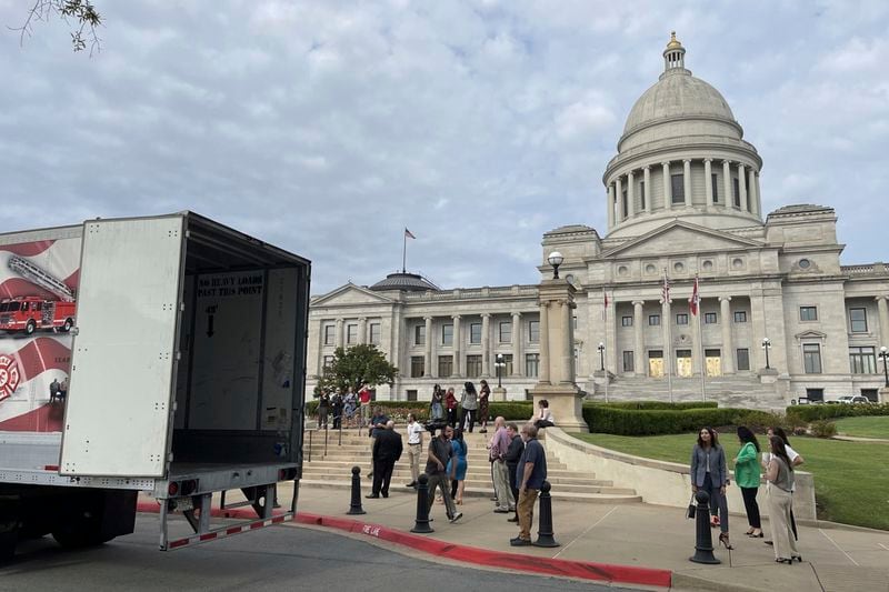 A crowd gathers to watch a tractor trailer holding a statue of Johnny Cash, depart from the Arkansas Capitol in Little Rock, Ark., Thursday, Sept. 5, 2024. (AP Photo/Andrew DeMillo)